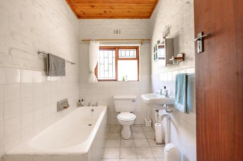 a bathroom with a tub and a toilet and a sink at Villa Kappri in Natureʼs Valley