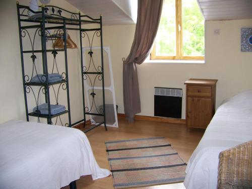 1 dormitorio con 2 camas, ventana y estante en L'âne Vert en Saint-Méard-de-Gurçon