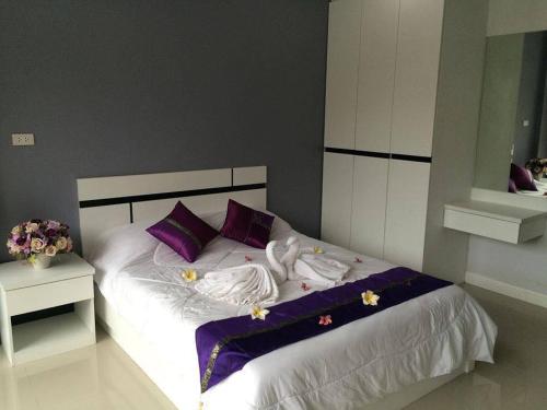 um quarto com uma cama com lençóis roxos e brancos e almofadas roxas em Pandora House by Mike Group em North Pattaya