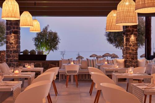 um restaurante com mesas brancas, cadeiras e luzes em Aqua Blue Beach Hotel em Perissa
