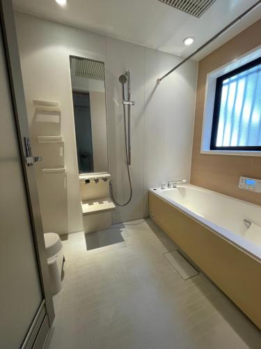 a bathroom with a tub and a toilet and a sink at ゲストハウスフォレ in Kukumo