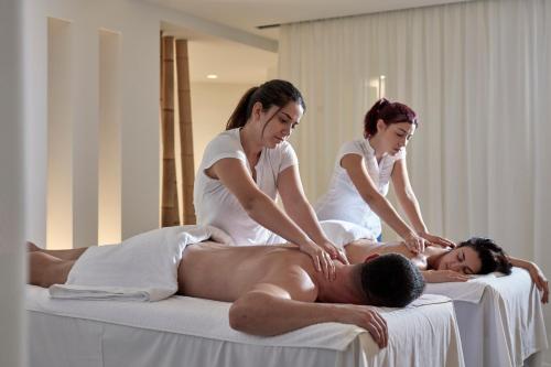 two women getting a man in a massage bed at Aqua Blue Beach Hotel in Perissa
