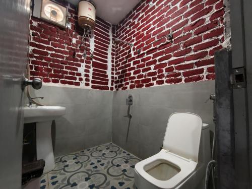 a bathroom with a white toilet and a brick wall at Hotel Indo Tiger by RawatHospitality in Tembhuida