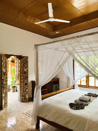 a bedroom with a white bed with a ceiling at Kubu Elsa Bali in Lovina