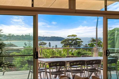 a table and chairs on a balcony with a view of the water at Aerial Blue Mollymook in Mollymook