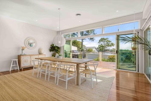 a dining room with a table and chairs at Aerial Blue Mollymook in Mollymook