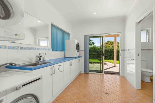 a white kitchen with a sink and a toilet at Aerial Blue Mollymook in Mollymook