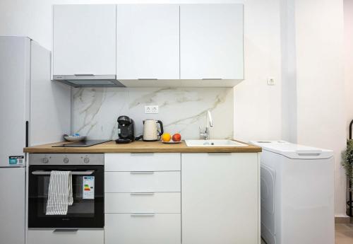 una cucina bianca con mobili bianchi e un lavandino di Modern Studio l King Bed & Work Corner ad Atene