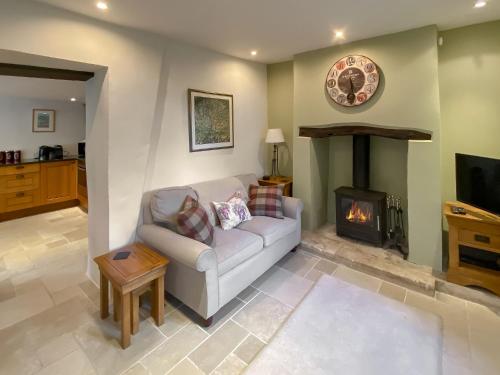 a living room with a couch and a fireplace at Folly Cottage in Avening
