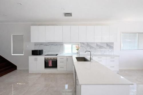 a white kitchen with white cabinets and a sink at Entire House walk to South Bank mater in Brisbane