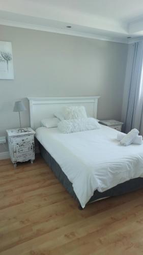 a bedroom with a large white bed and a wooden floor at Blouberg Heights in Cape Town