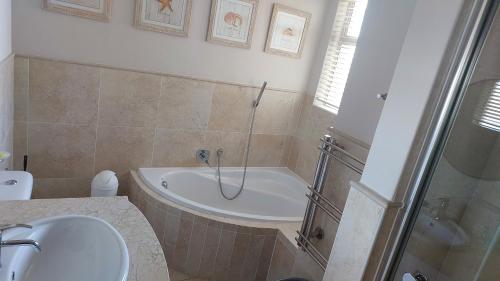 a bathroom with a tub and a sink and a shower at Blouberg Heights in Cape Town