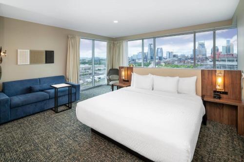 a hotel room with a bed and a blue couch at La Quinta Inn & Suites by Wyndham Nashville Downtown Stadium in Nashville
