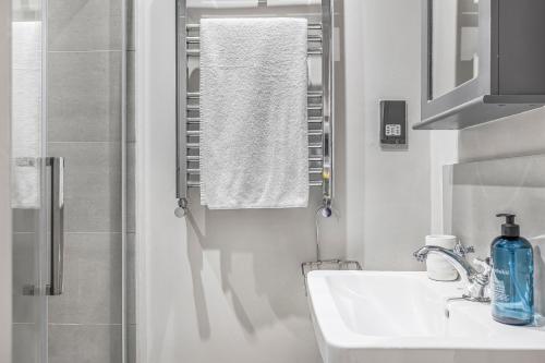 a white bathroom with a sink and a shower at Well Appointed Garden Condo in Kensington Olympia in London