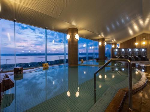 a large swimming pool with a view of the ocean at KAMENOI HOTEL Itako in Itako