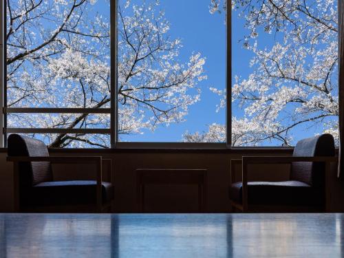 a table and two chairs in a room with windows at KAMENOI HOTEL Itako in Itako