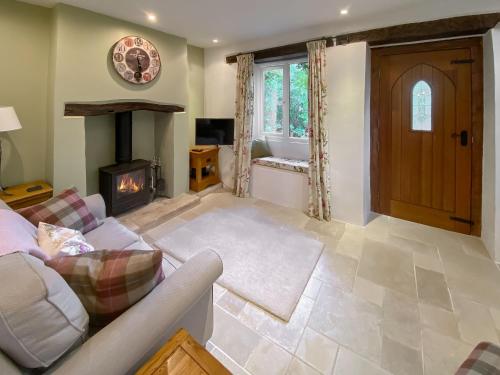 a living room with a couch and a fireplace at Folly Cottage in Avening