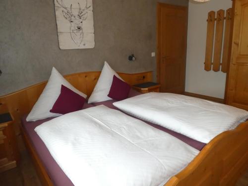 a bedroom with a bed with white and purple pillows at Gästehaus Bergblick in Wallgau