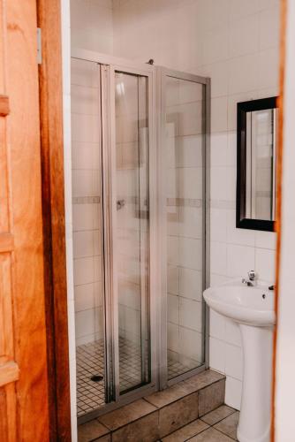 a bathroom with a glass shower and a sink at La Rona Hospitality Services in Rustenburg