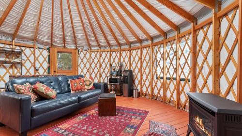a living room with a black leather couch in a yurt at Yurt 1 - The Prospector in Idaho City