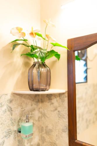 a vase with flowers sitting on a shelf next to a mirror at Quinta da Praia by Semper Felix in Calangute