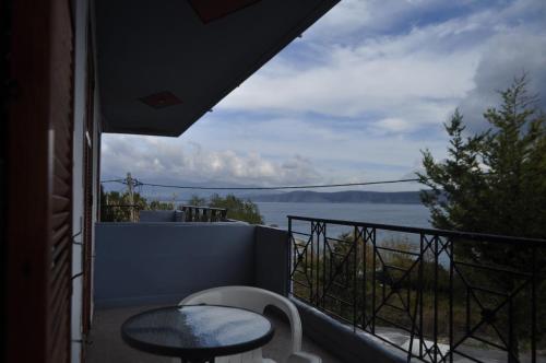 balcón con mesa y vistas al agua en Hotel Limni, en Agios Panteleimon