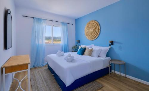 a blue bedroom with a large bed with a window at Greek Village - Latchi הכפר היווני - כשר in Polis Chrysochous