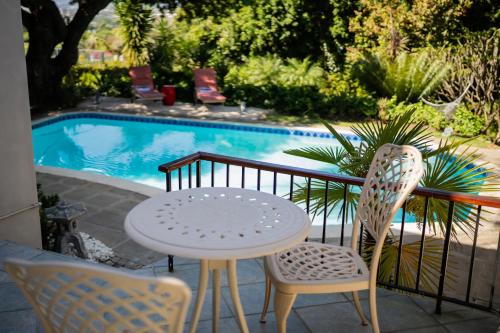 a table and chairs next to a swimming pool at De Wingerd Wijnland Lodge in Paarl