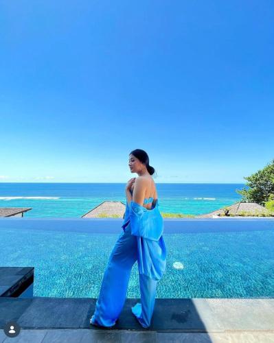a woman in a blue dress standing next to the ocean at Nusa Dua Cliff Ocean View with Private Beach in Nusa Dua