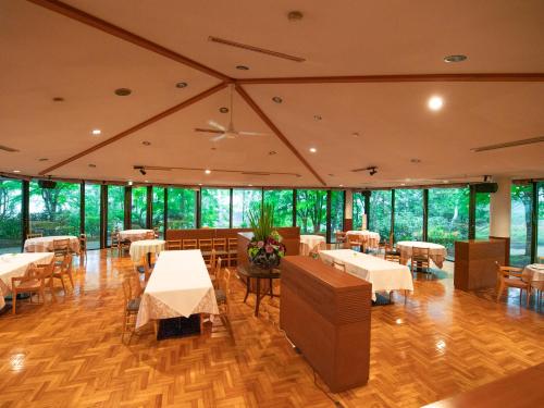 a restaurant with tables and chairs and windows at Tabist Hotel Colosseum Inn Tateshina in Tateshina