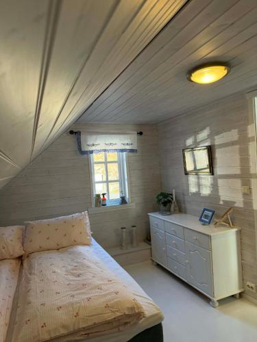 a bedroom with a bed and a dresser and a window at Cabin by the lake in Sveio