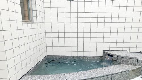 a tub in a white tiled shower with water at Livemax Resort Yatsugatake Kogen in Hokuto