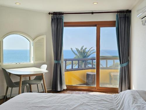 a bedroom with a bed and a view of the ocean at Tteuribada Pension in Seogwipo