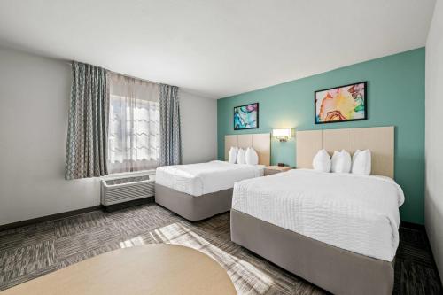 a hotel room with two beds and a window at MainStay Suites Greensboro in Greensboro