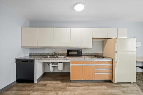 a kitchen with white cabinets and a refrigerator at MainStay Suites Greensboro in Greensboro