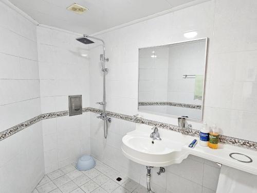 a white bathroom with a sink and a mirror at Tteuribada Pension in Seogwipo