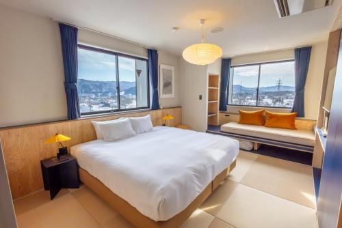 a bedroom with a large bed and two windows at evo Hotel Hakuba in Hakuba