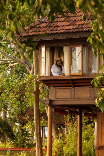 a man looking out the window of a tree house at Coconut Lagoon Kumarakom - A CGH Earth Experience in Kumarakom