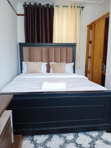 a bedroom with a large bed with a black headboard at Belaire BnB Ruaka 1 in Nairobi
