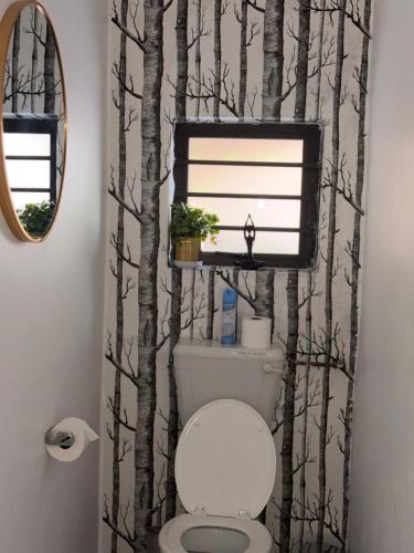 a bathroom with a toilet with a tree themed shower curtain at @Oudam in Montagu