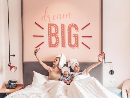 a woman and child laying in bed with a dream big sign at Rove At The Park in Dubai