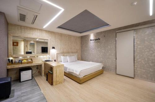 a bedroom with a bed and a desk in a room at Daegu Play and Stay Hotel in Daegu