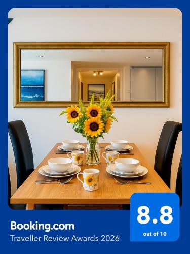 a table with a vase of sunflowers on it at Sidemersey Livings- Rare Accessible 2BR Liverpool City Centre Apartment in Liverpool