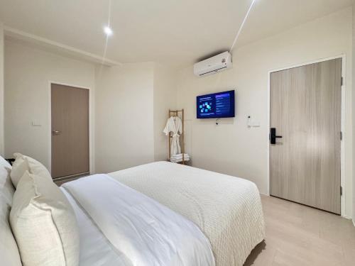 a white bedroom with a bed and a tv at Quies Hotel in Krabi