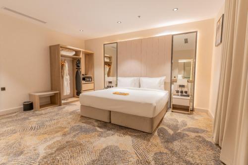 a bedroom with a white bed and a large mirror at فندق حياة تاون حقل in Ḩaql