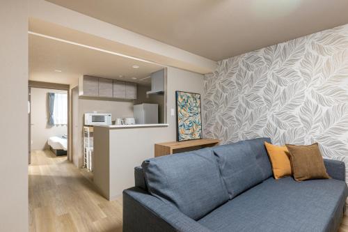 a living room with a blue couch and a kitchen at C L Susukino in Sapporo