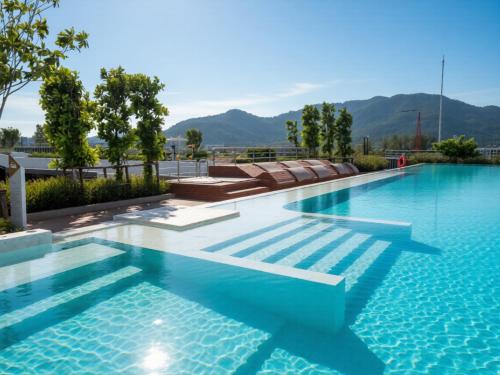 a swimming pool with blue water and mountains in the background at Laguna SkyPark new brand apartments in Phuket