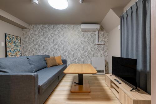 a living room with a blue couch and a television at C L Susukino in Sapporo