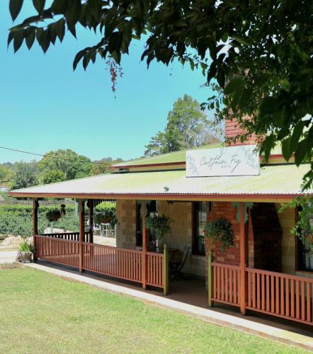 a building with a porch with a sign on it at Curtain Fig Motel in Yungaburra