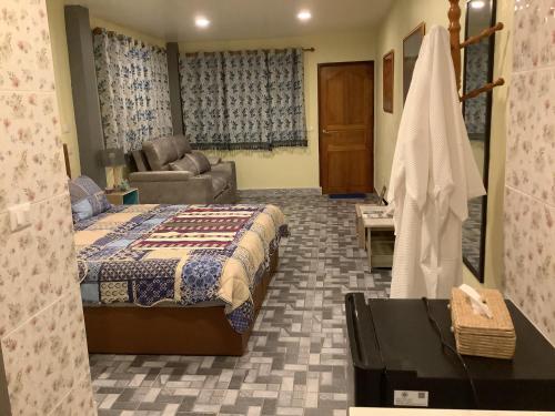 a bedroom with a bed and a couch and a chair at CC Homestay in Surin